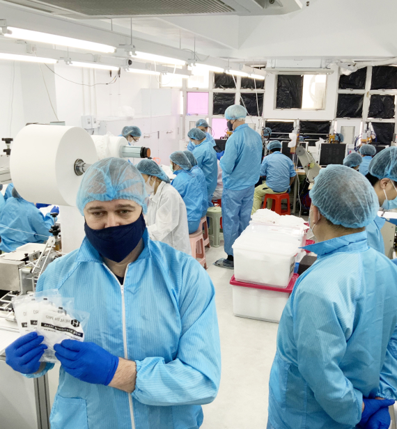 people in blue coats and masks work at the factory
